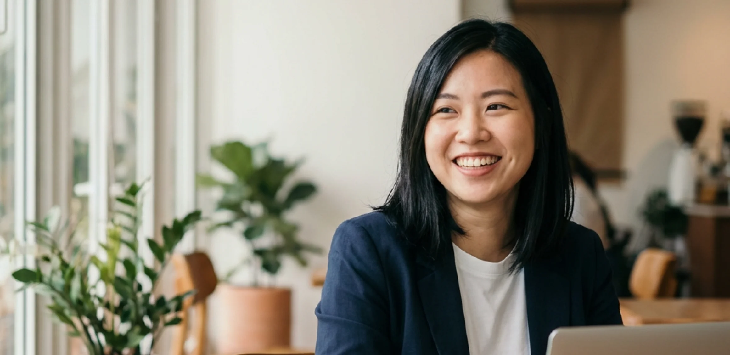 A smiling Malaysian professional working in a bright cafe